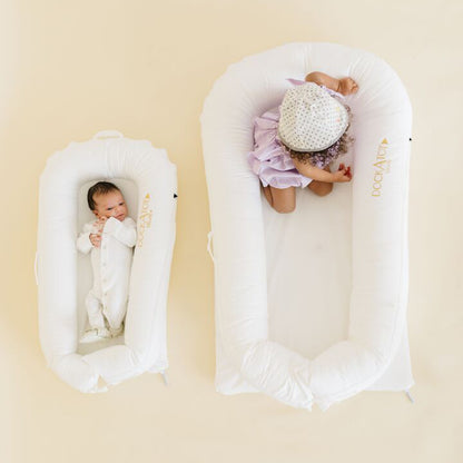 赤ちゃん2人が並んでDockATotでくつろぐシーン（DeluxeとGrandサイズ比較）